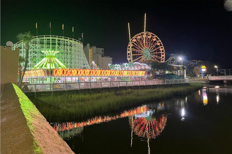 The lights of Family Kingdom Amusement Park at Myrtle Beach SC reflect in Withers Swash at night. 