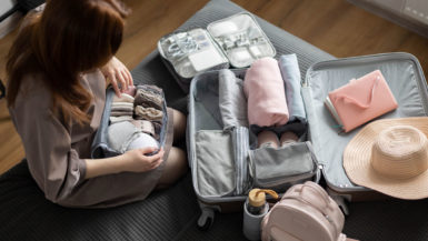 A woman with long brown hair sits near an open suitcase; everything looks very well organized.