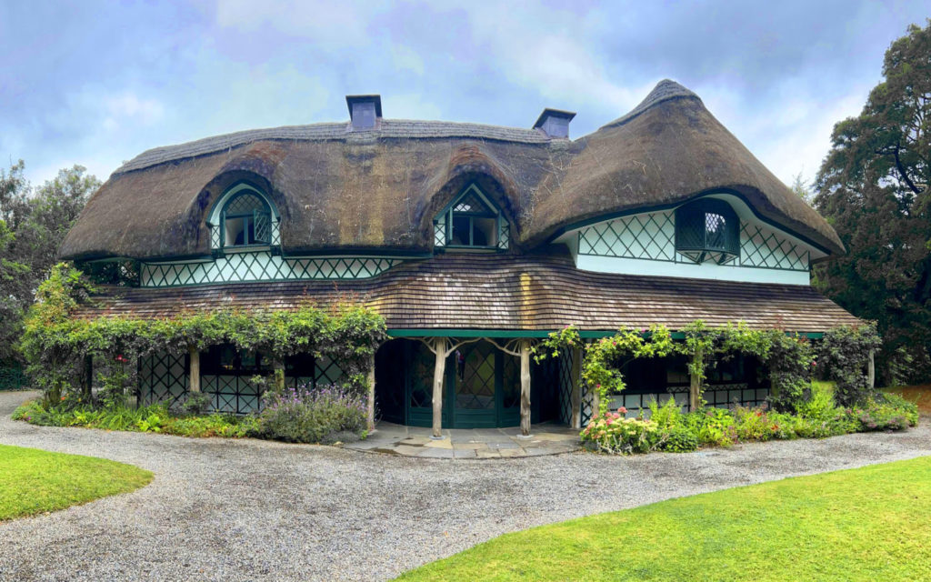 A beautiful house with a thatched roof and flowers.