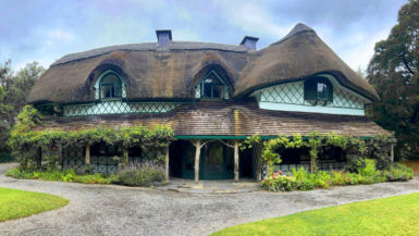 A beautiful house with a thatched roof and flowers.