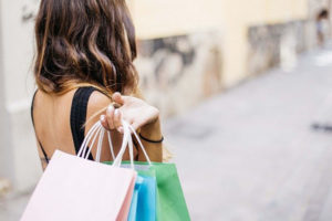 A woman carrying shopping bags, with an artistically blurred background.