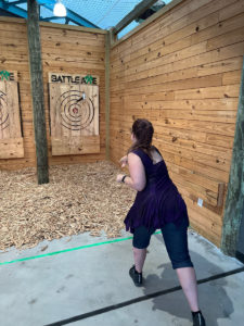 A woman, seen from the back, throws a hatchet at a wooden target at Battle Works in Atlantic Beach on the Crystal Coast.